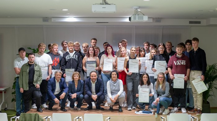 Diplomfeier Gruppenfoto von jungen Menschen mit Zertifikaten bei einer Abschlussfeier