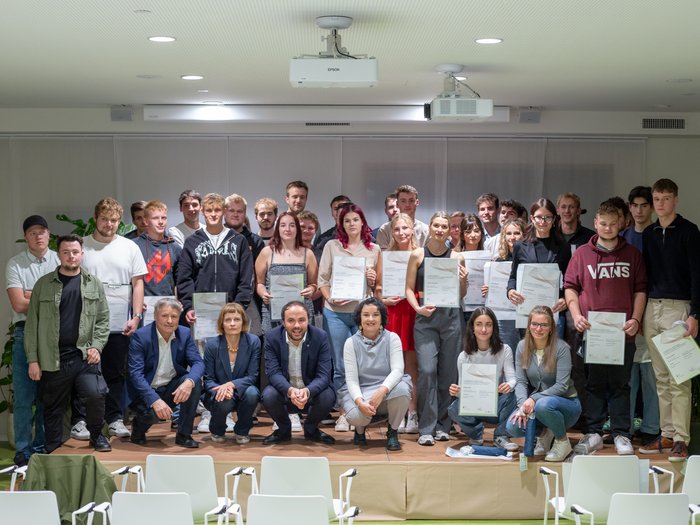 Diplomfeier Gruppenfoto von jungen Menschen mit Zertifikaten bei einer Abschlussfeier