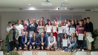 News Gruppenfoto von jungen Menschen mit Zertifikaten bei einer Abschlussfeier