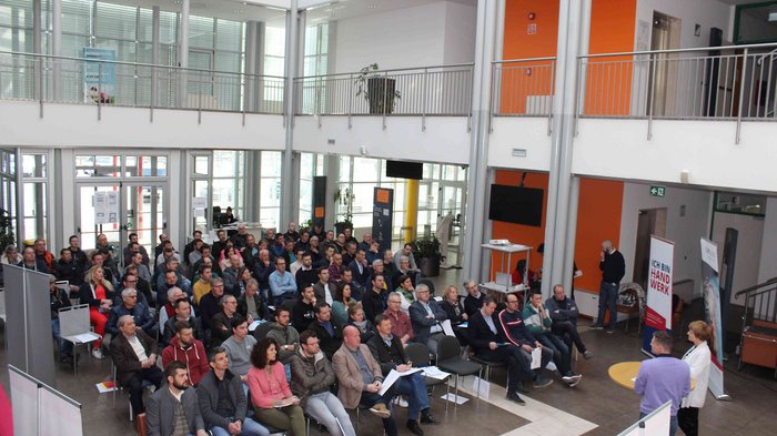 Umbruch bei den Berufsgemeinschaften der Karosserietechniker/innen und KFZ-Mechatroniker/innen Große Gruppe von Menschen bei einer Präsentation in einem modernen Gebäude