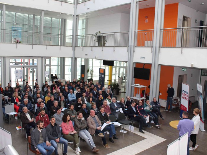 Umbruch bei den Berufsgemeinschaften der Karosserietechniker/innen und KFZ-Mechatroniker/innen Große Gruppe von Menschen bei einer Präsentation in einem modernen Gebäude