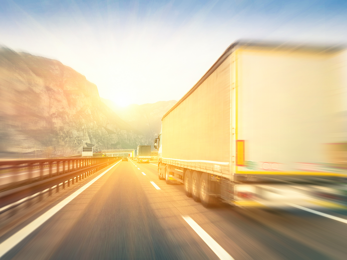 Barometro dell’economia IRE – Estate 2025 Buon clima di fiducia nei trasporti e nei servizi Camion in velocità su autostrada con paesaggio montano al tramonto
