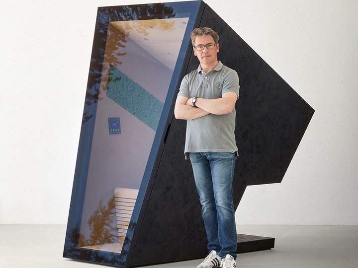 Tischlerei Declara Mann steht vor modernem schwarzen Sitzwürfel mit großen Glasfenster
