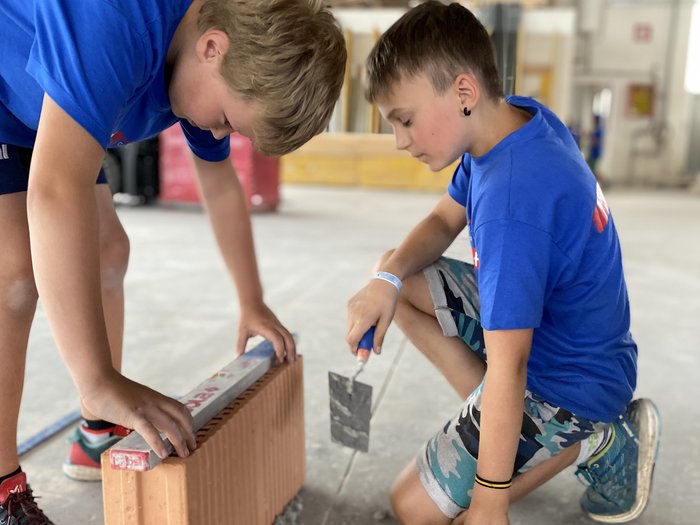 Bild 2: Interessiert und geschickt am Werk während der Projektwoche „Fleißige Baumeister“ © lvh.apa Zwei Jungen arbeiten gemeinsam an einer Mauer mit Kelle und Ziegelstein