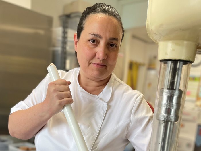 Warum der Frühling nach gutem Speiseeis schmeckt Frau in weißer Arbeitskleidung hält Stab in einer Küche