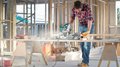Der Südtiroler Zimmerer-Meistertitel wird jetzt in Deutschland anerkannt Mann sägt Holz mit Kappsäge in Baustelle mit offenem Holzrahmen