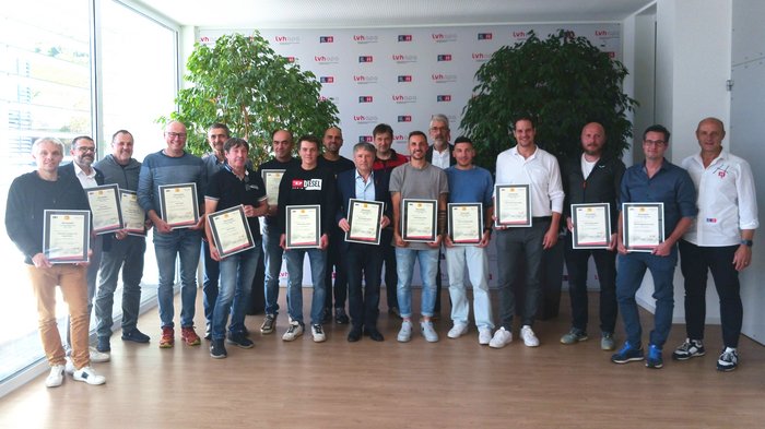 Convegno Marchio-E 2025: responsabilità, innovazione e sicurezza al centro dell’elettrotecnica Gruppo di uomini con certificati in una stanza con piante e logo aziendale sullo sfondo