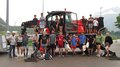 Kinder und Jugendliche lernen die Welt der Baumaschinen Gruppe von Jugendlichen und Erwachsenen vor einem roten Arbeitsfahrzeug im Freien
