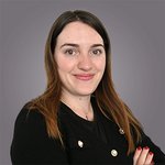 Il team di lvh.apa Ritratto di donna sorridente con capelli castani lunghi su sfondo grigio