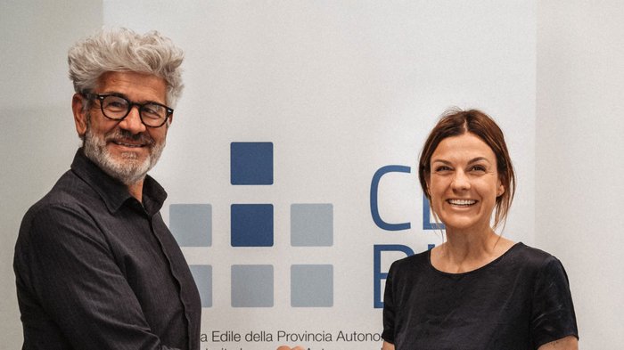 Markus Bernard al vertice della Cassa Edile della Provincia Autonoma di Bolzano Due persone sorridenti davanti a una parete con grafica e scritte blu