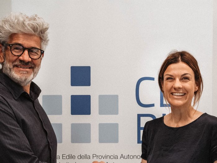 Markus Bernard al vertice della Cassa Edile della Provincia Autonoma di Bolzano Due persone sorridenti davanti a una parete con grafica e scritte blu