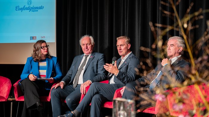 Tag des Handwerks Vier Personen in Anzügen sprechen auf einer Podiumsdiskussion bei Confartigianato Imprese.