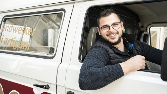 Alexander Dallio ist neuer Landesobmann der Junghandwerker Lächelnder Handwerker sitzt im Transporter und schaut aus dem Fenster