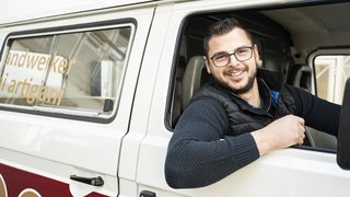 News Lächelnder Handwerker sitzt im Transporter und schaut aus dem Fenster