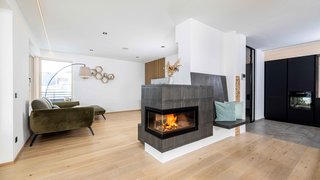 News Moderner Wohnraum mit Kamin, grünem Sofa und Holzboden
