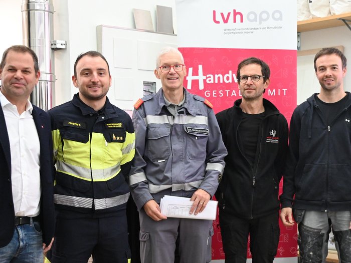 Sicheres Heizen Fünf Männer in Arbeits- und Feuerwehruniform vor einem LVH-Banner