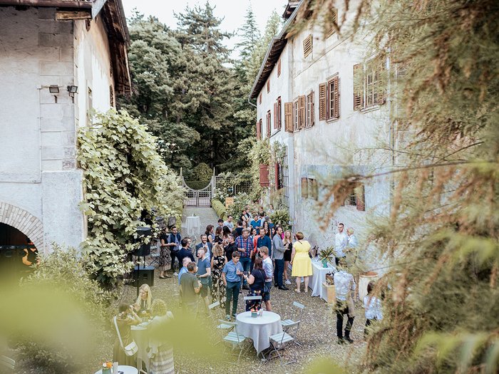 Generation-H Aperitif Menschen bei einer Gartenparty zwischen alten Gebäuden im Freien
