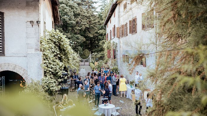 Generation-H Aperitif Menschen bei einer Gartenparty zwischen alten Gebäuden im Freien