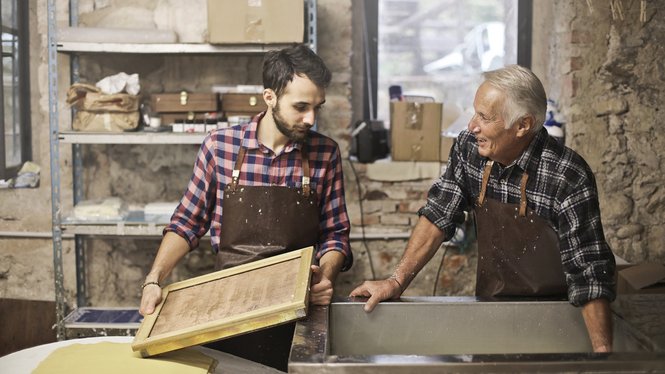 Home Uomo giovane e anziano che producono carta artigianale in laboratorio