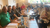 Home Gruppo di persone sedute a tavoli di legno in un ristorante, una donna tiene un bambino in braccio