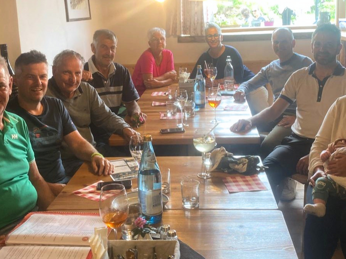 Zusammenhalt und Tradition Gruppe von Menschen sitzt an Holztischen in einem Restaurant, eine Frau hält ein Baby