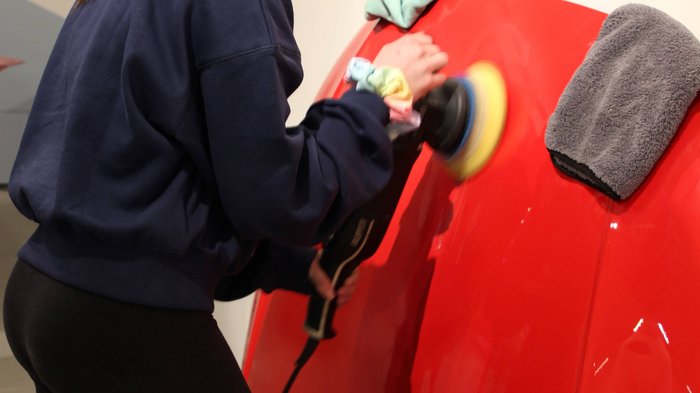Una settimana intorno all‘artigianato Donna lucida una carrozzeria rossa con una macchina lucidatrice