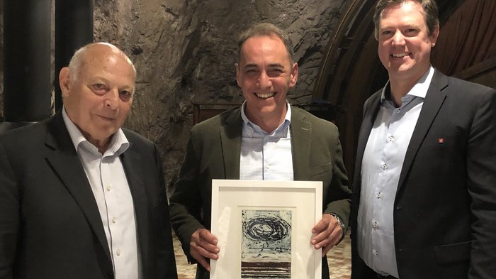 Bilaterale Körperschaft: verdiente Akteure geehrt Drei Männer, einer hält gerahmtes Kunstwerk in einer Höhle