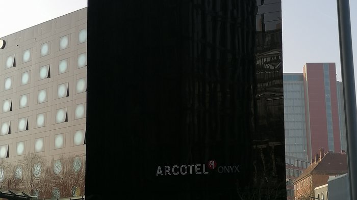 Die Althandwerker besuchen Hamburg Schwarzes Gebäude des Arcotel Onyx Hotels mit Menschen davor an einem Platz