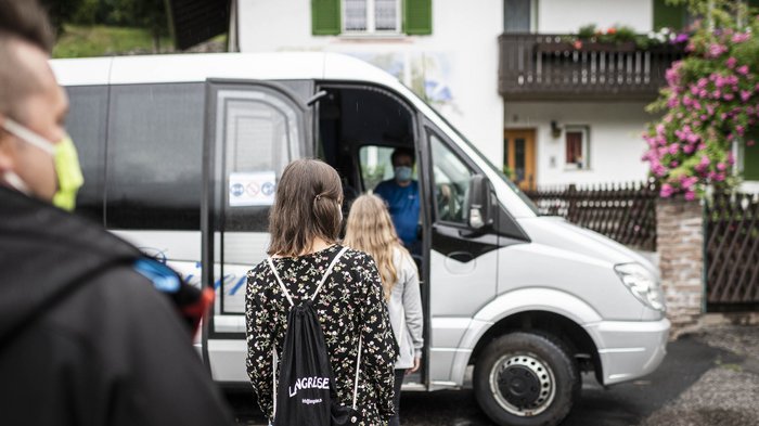 Mietwagenunternehmen als Teil des Wirtschaftskreislaufes © Hannes Niederkofler Menschen mit Masken warten, um in einen weißen Kleinbus einzusteigen