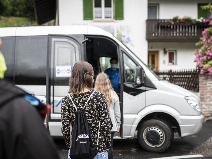 Mietwagenunternehmen als Teil des Wirtschaftskreislaufes © Hannes Niederkofler Menschen mit Masken warten, um in einen weißen Kleinbus einzusteigen