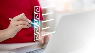 News Hand markiert Punkte auf digitaler Checkliste vor Laptop
