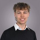 Elektromechaniker Junger Mann mit lockigem Haar und weißem Hemd unter schwarzem Pullover