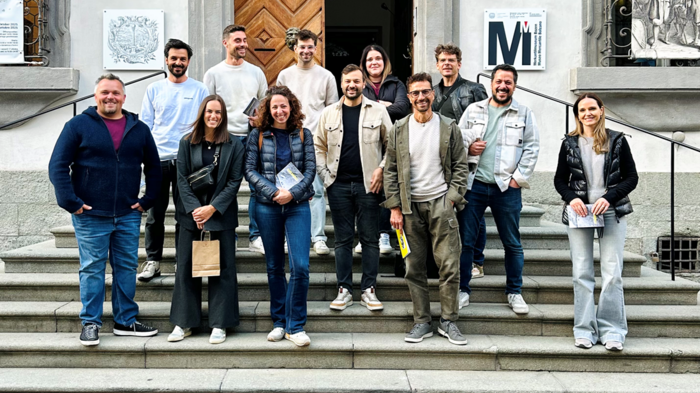 Fotografia tra artigianato, creatività e responsabilità Gruppo di 13 persone sulle scale davanti a edificio storico