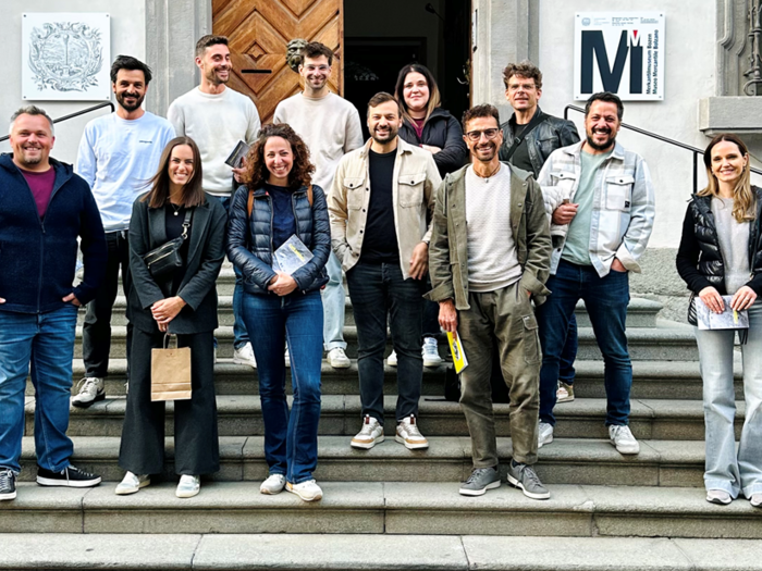 Fotografia tra artigianato, creatività e responsabilità Gruppo di 13 persone sulle scale davanti a edificio storico