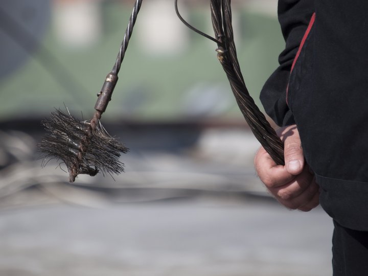 Kaminkehrer Hand hält einen Schornsteinfegerbesen mit Drahtborsten