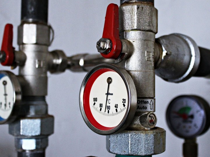 Heizungs-, Lüftungs- und Sanitärtechniker Nahaufnahme von Rohrleitungen mit Temperaturmanometern und roten Ventilen