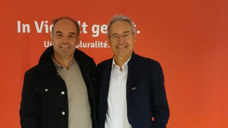 News Zwei Männer lächeln vor rotem Hintergrund mit Text in Deutsch und Französisch