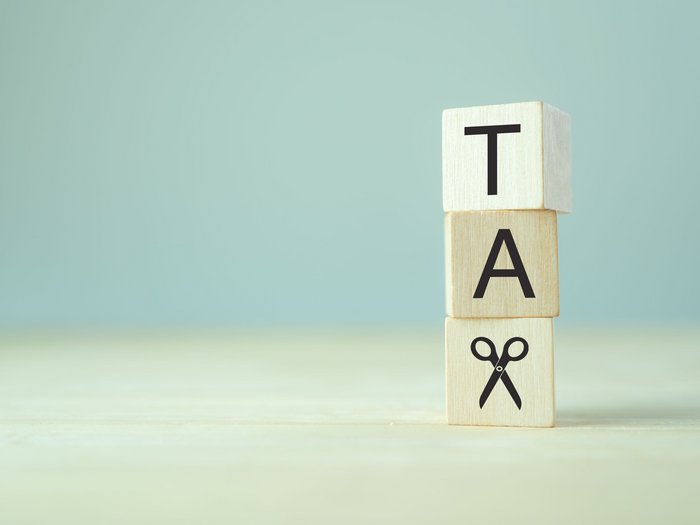 Ein gerechteres Steuersystem Holzwürfel mit Buchstaben T, A und einer Schere auf hellem Hintergrund