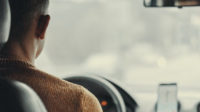 © Viktor Bystrov/Unsplash.com Mann von hinten beim Autofahren mit Navigationsgerät am Armaturenbrett