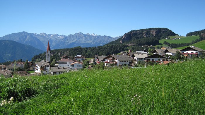 Comeback für den ländlichen Raum Bergdorf mit grünen Wiesen und Alpen im Hintergrund unter blauem Himmel