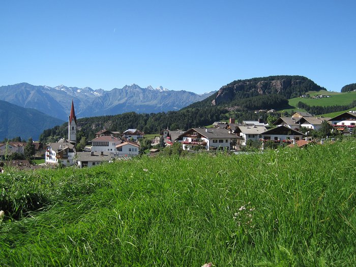 Comeback für den ländlichen Raum Bergdorf mit grünen Wiesen und Alpen im Hintergrund unter blauem Himmel