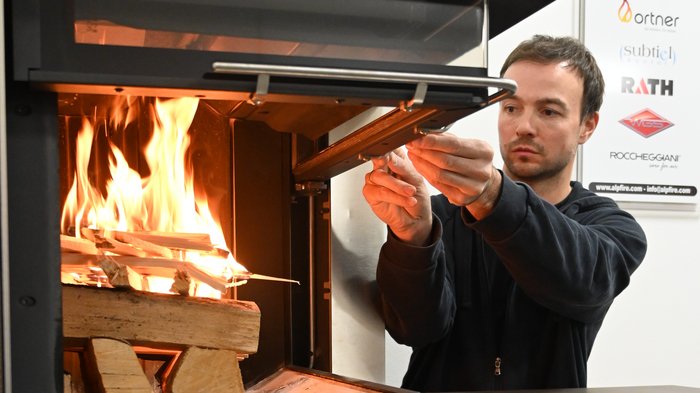 Al sicuro durante la stagione del riscaldamento Uomo accende pezzi di legno in una stufa