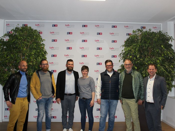 Beste Jungmetzgerin ausgezeichnet Sieben Personen stehen vor einer Wand mit LVH-APA-Logos und Pflanzen