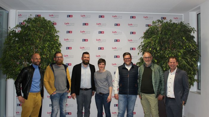 Beste Jungmetzgerin ausgezeichnet Sieben Personen stehen vor einer Wand mit LVH-APA-Logos und Pflanzen