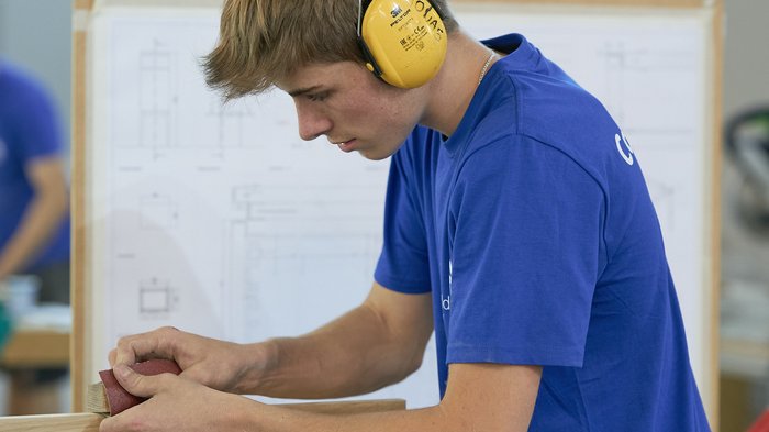 WorldSkills Italy: Obiettivo Lione Giovane uomo carteggia un pezzo di legno in laboratorio