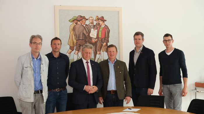 “Il regolamento dell'UE sulla deforestazione mette a rischio la gestione sostenibile delle foreste”. Sei uomini in piedi intorno a un tavolo da conferenza davanti a un dipinto