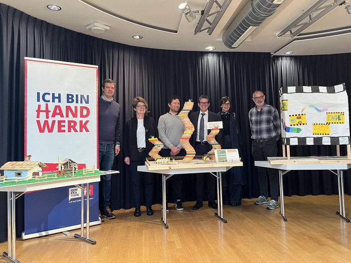 Handwerkliches Geschick und Kreativität: Prämierung des „Abenteuer Handwerk“-Wettbewerbs Gruppe von sechs Personen steht hinter drei Tischen mit Modellen und Banner Ich bin Handwerk