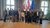 Foto di gruppo di persone davanti alle bandiere austriache e UE in una sala