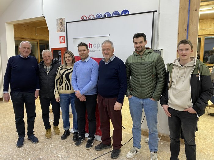 Forte coesione e prospettive future in Valle Aurina Sette persone in piedi davanti a un podio e banner in ambiente interno