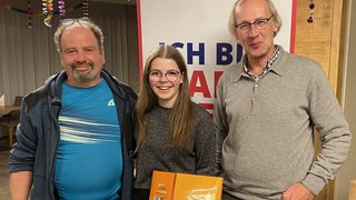 News Drei lächelnde Personen, junge Frau hält Lindt Schokoladenbox